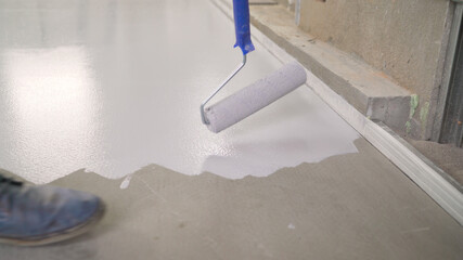 Application of white paint to the concrete floor. Primer for concrete floor before finishing....