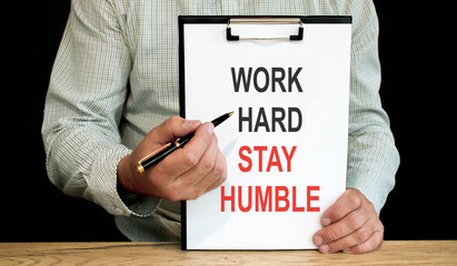 Work hard stay humble word inscription on white card paper sheet in hands of a businessman. recap concept. white paper
