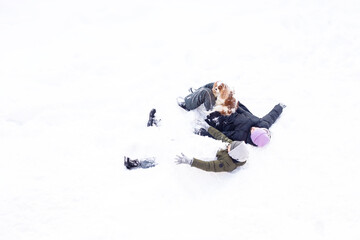 girl, boy, kids and dog having fun outdoors, winter snow day, family time, sister and brother play angel in warm clothes. Top view