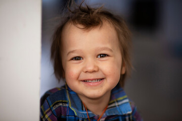 Cheerful kid 3-4 years old in a blue retro shirt in a checkered smile on a white background