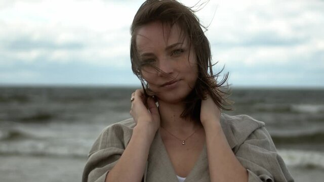 Beautiful Young Woman Model Mysteriously and Seductive Looking into Camera on a Beach with Wind in Her Hair.
