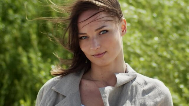 Beautiful young woman brunette looking into camera on a windy day.