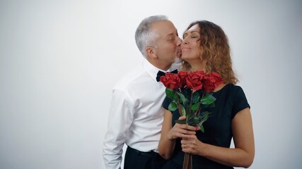 A loving elderly man gives his elderly wife red roses for the anniversary.