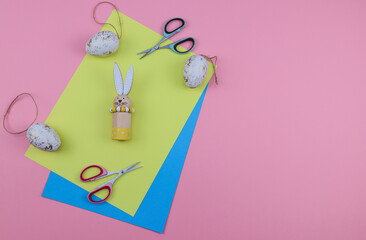 
Scissors and paper.
Colored paper scissors and Easter eggs with a bunny on a pink background with a place for text on the right, close-up top view.