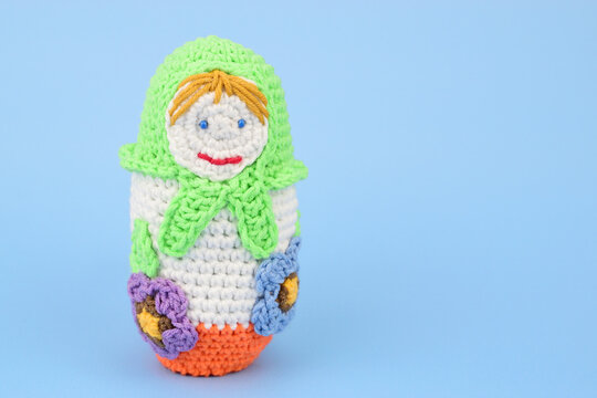 Knitted doll in a green shawl isolated on a blue background.