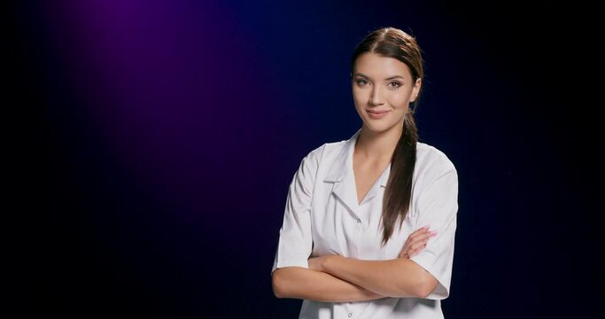 A brunette model in a white blouse smiles at the camera while posing against a dark purple studio backdrop with copy space.