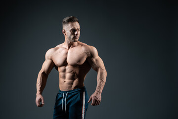young handsome sportsman bodybuilder posing on dark background