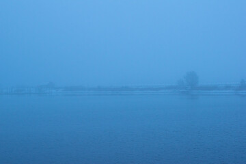 View of foggy lake in winter with snow