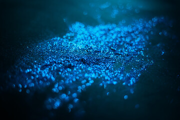Blue glitter texture. Sequins scattered on a black background. Shimmering effect. Bokeh.