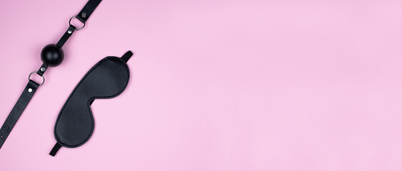 A variety of sex toys (eye mask, harness, gag in the mouth) are presented on a pink background. The image is suitable for advertising and promoting a sex shop. Banner - obrazy, fototapety, plakaty