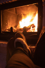 Young man's feet getting warm by a fireplace. 