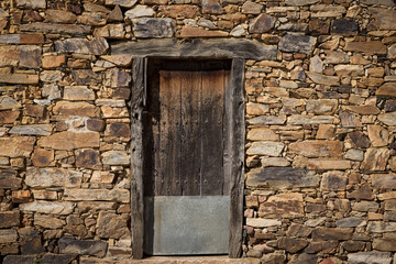 ancient wooden door on an antique stone wall of a rustic house