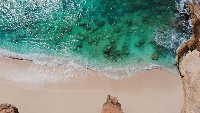 Top view of a beautiful blue turquoise beach with waves washing up the shores on the Caribbean. White sandy beaches with ocean clashing against the shores in the Caribbean. 