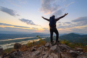 Obraz premium Rear view of man open arms standing on the cliff enjoying watch Mekong river at sunrise in Nong Khai, Thailand