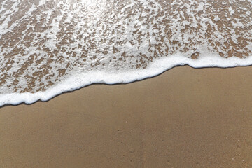 Soft waves of the blue ocean on the sandy beach, aqua Foam bubbles, summer Holiday Background.
