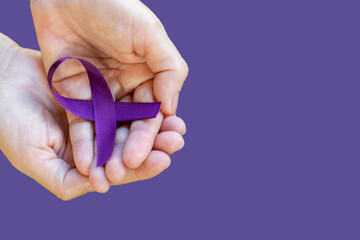 hands holding ribbon with purple bow. February Roxo, awareness month about Lupus, Fibromyalgia and...