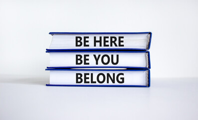 Belong symbol. Books with words 'be here, be you, belong' on beautiful white table, white...