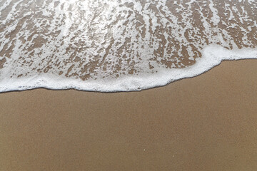 Fototapeta na wymiar Soft waves of the blue ocean on the sandy beach, aqua Foam bubbles, summer Holiday Background.