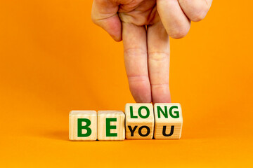 Be you, belong symbol. Businessman hand turns cubes and changes words 'be you' to 'belong'. Beautiful orange background. Business, belonging and be you, belong concept. Copy space.