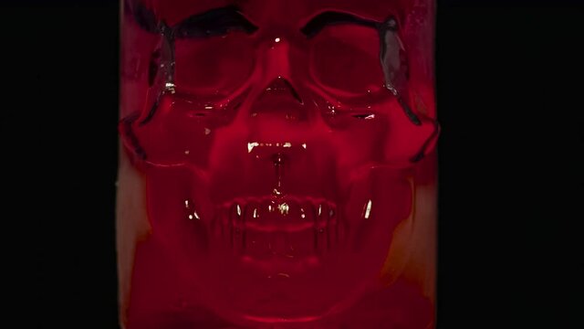 Melting Red Ice Skull. Timelapse. Ice skull covered with frost quickly melts and glistening disappears in the dark