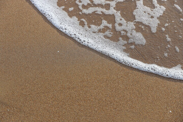 Soft waves of the blue ocean on the sandy beach, aqua Foam bubbles, summer Holiday Background.