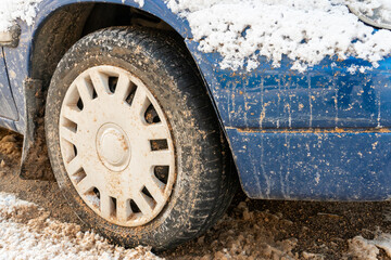 Parts of the car are covered with snow and ice after a snowfall. Wheel close-up in dirt and anti-icing reagents. Big frosts and a lot of snow in the city. Problems on winter slippery roads.