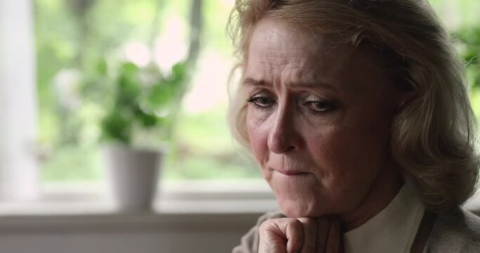 Close up head shot stressed middle aged old 60s woman worrying about difficult life situation, feeling insecure frustrated alone indoors, suffering from mental disease or psychological problems.