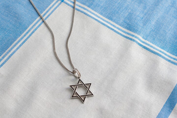 Star of David necklace, Magen David, on white-blue fabric.