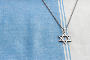 Star of David necklace, Magen David, on white-blue fabric.