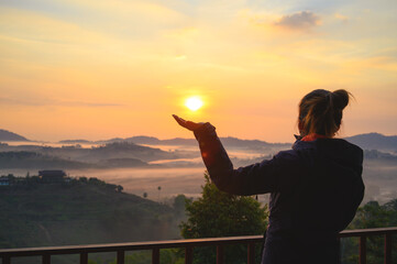 Fototapeta premium Asian woman enjoys the view of misty landscape in morning at Khao Kho hill in Phetchabun, Thailand