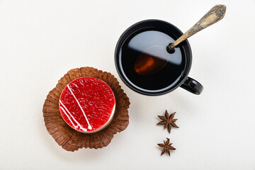 Tea in a black mug with a spoon, with a cake and anise stars on a light background
