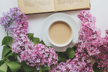 spring cozy composition flat lay coffee cup, book, lilac branches, spring season concept
