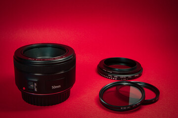 Close up 50 mm prime lens. polarized filter, a uv filter and a neutral density filter behind with a red background.