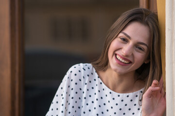 Cheerful young woman leaning on a wall and smiling, with copy space.