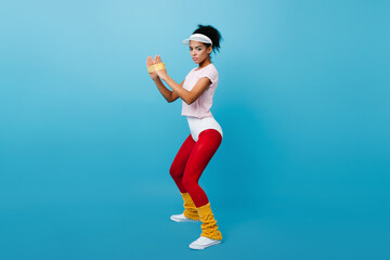 Pretty black girl using expander. Studio shot of training african woman wears aerobics clothes.