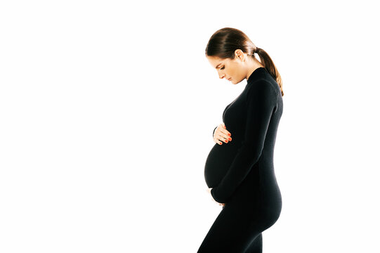 Studio maternity portrait of gorgeous young woman, posing on white background, wearing black turtle neck dress