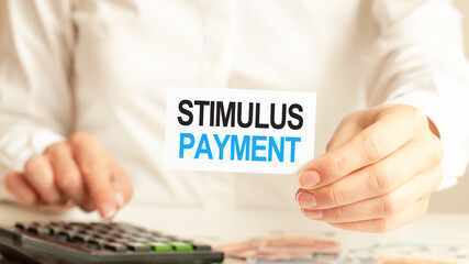 A woman a holding piece of paper with the text: STIMULUS PAYMENT. Finance and economics concept.