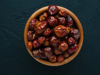 Whole small dry red hot pepper on bowl in black stone background. Spices and seasonings for cooking. Dried fruits of Capsicum frutescens, used as hot spice and for tabasco sauce. Top view. Soft focus