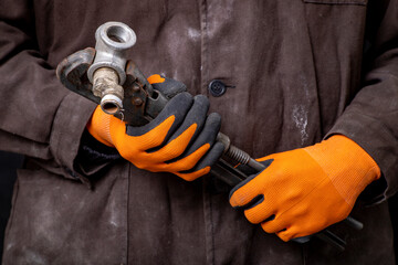 Plumber holding a wrench and pipes in his hands. Work in a mechanical workshop.