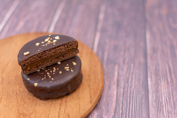 A chocolate alfajor filled with dulce de leche, on a wooden board