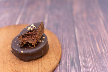 A chocolate alfajor filled with dulce de leche, on a wooden board