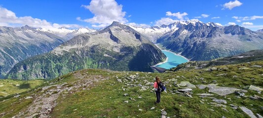 Girl admiring the view of Alpine lake Schlegeis in the valley Zillertal, Austrian Alps