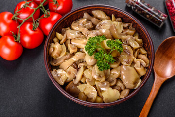 Fresh delicious spicy canned mushrooms with spices and herbs in ceramic dishes