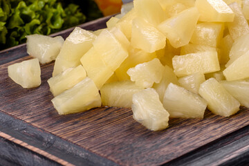 Pineapple canned with pieces on a wooden cutting board