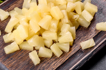 Pineapple canned with pieces on a wooden cutting board
