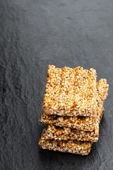 Sesame seed honey bars on black stone background