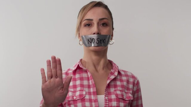 The young woman who wanted to give a social message taped her mouth, the tape on her mouth says no sex. Message given silently. The woman says safe sex with her hands.
