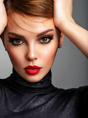 Fototapeta na wymiar Beautiful girl with red lips and short hair. Pretty face of an young sensual woman. Closeup portrait of a model with bright makeup on a face. Attractive female posing at studio in black closes.