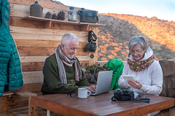 Two carefree elderly people work outdoors with the use of technological devices. Active and modern...