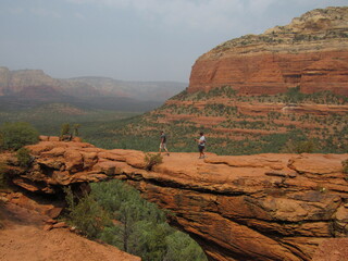An unrecognizable person on Devil's Bridge, the natural arch formation, with red rock mountains in the background located in Sedona, Arizona